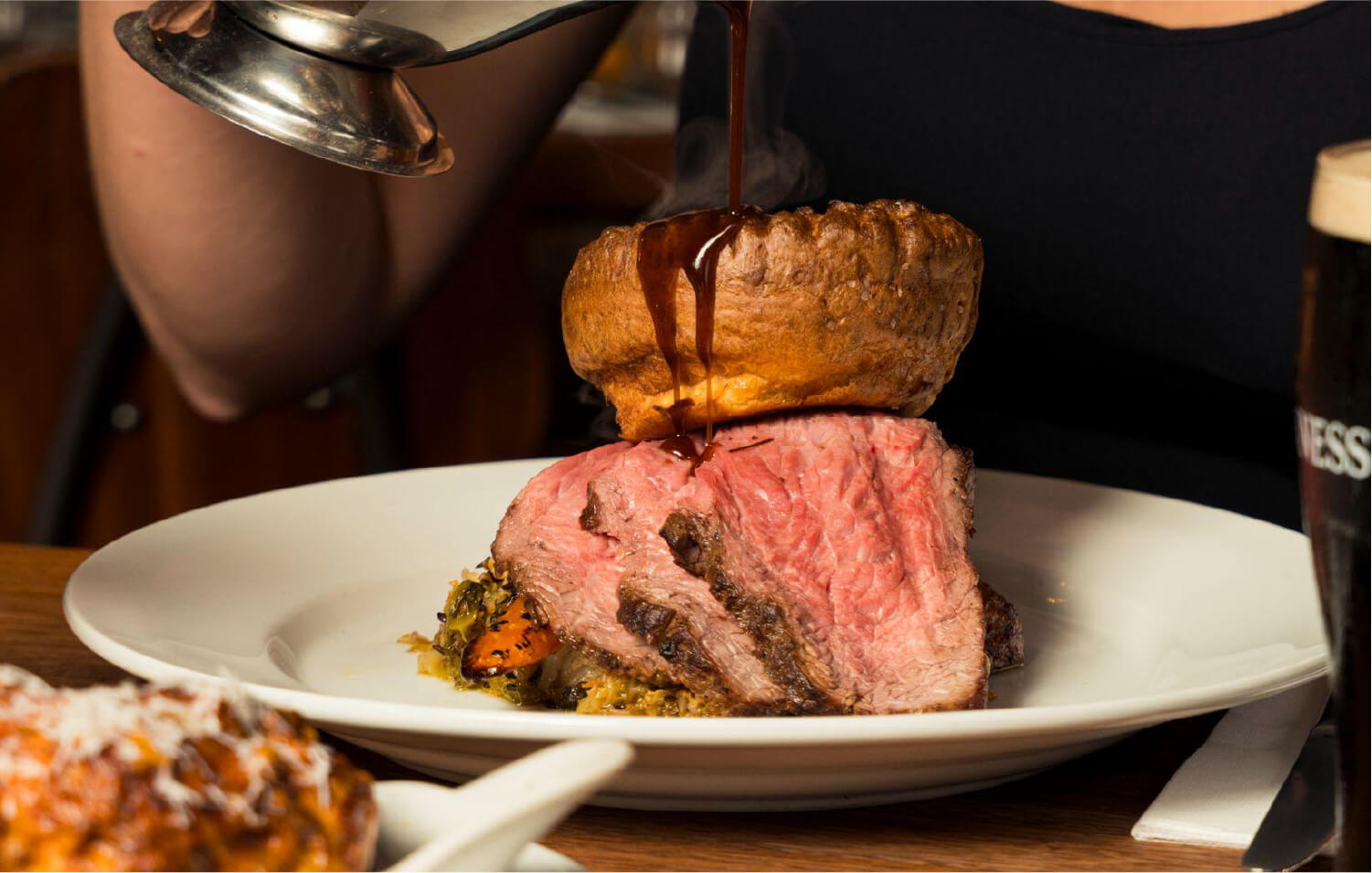 A woman pouring gravy onto a roast dinner