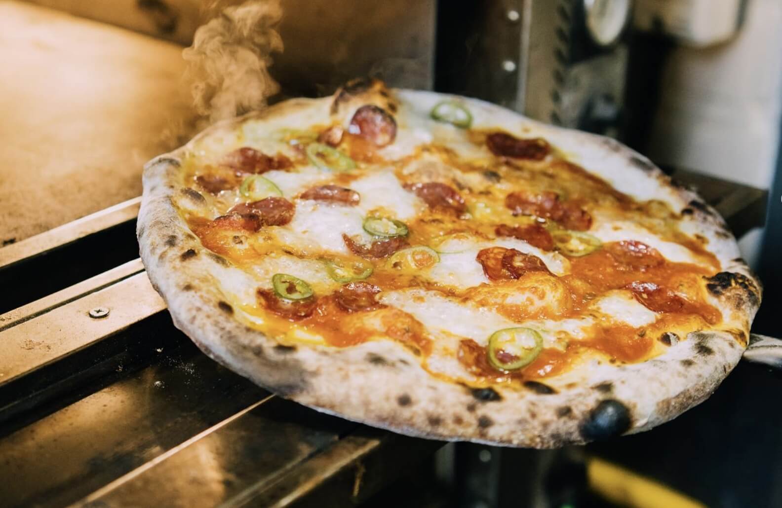 Fresh pizza coming down the oven